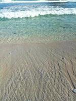 små vågor på den vita sandstranden foto