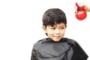en pojke sprayas hans hår av frisör isolerade över vit bakgrund foto