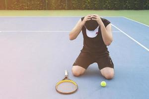 ledsen tennisspelare sitter på banan efter att ha förlorat en match foto