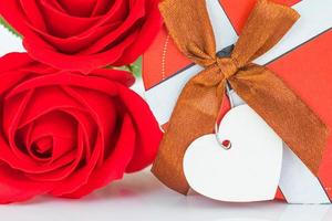 röda rosor och hjärtformad låda på vitt foto
