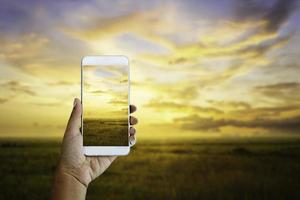 handhåll smartphone och solnedgång landskap foto