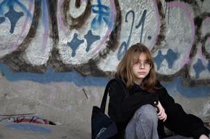 st. Petersburg, Ryssland, 2022-01-06. en tonårsflicka sitter i en övergiven byggnad målad med graffiti och röker foto