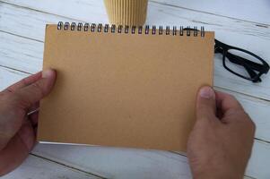 hand som håller ett tomt brunt anteckningsblock med utrymme som kan anpassas för text eller idéer. kopiera utrymme för idéer foto