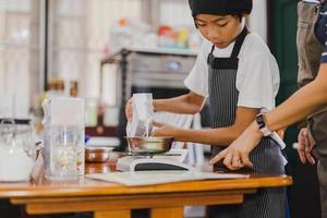 ung pojke mäta ingrediens för bakning i köket. foto