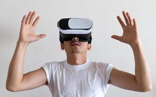 ung man bär virtuell verklighet glasögon headset på grå bakgrund. begreppet vr, videospel, framtid, prylar och teknik. foto