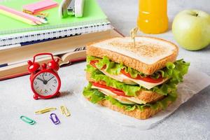 hälsosam lunch till skolan med smörgås, färskt äpple och apelsinjuice. diverse färgglada skolmaterial. kopieringsutrymme. foto