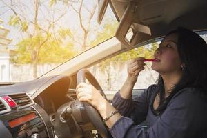 kvinna som gör upp hennes ansikte med läppstift medan du kör bil, osäkert beteende foto
