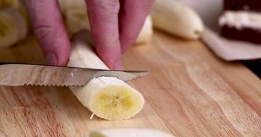 skära en mogen gul banan i bitar under tillagningen foto