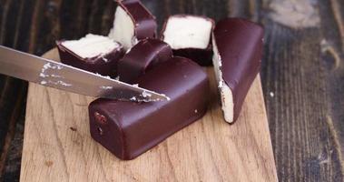 skär i bitar ostmassa i chokladglasyr med socker foto