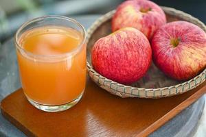 äppelcidervinäger naturliga botemedel och botemedel för vanligt hälsotillstånd, rå och ofiltrerad organisk äppelcidervinäger i glas med äppelfrukt på korgen på träbordet foto