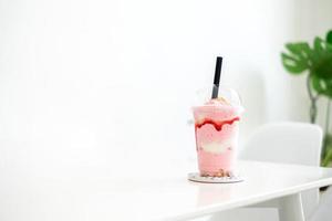 jordgubbssmoothie milkshake i koppen på vitt bord i kaféet, konceptmat, dryck och hälsa, kopieringsutrymme foto