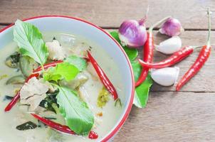 grön kycklingcurry med rå kryddig ingrediens thailändsk traditionell mat på brun träbakgrund foto