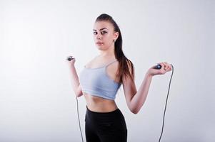 glada attraktiva unga fitness kvinna i topp och svarta leggings med hopprep isolerad över vit bakgrund. foto