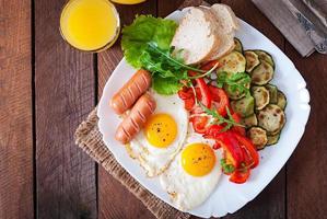 engelsk frukost - stekt ägg, korv, zucchini och paprika foto