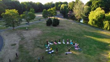 grupp kvinnor som tränar yoga tillsammans i den offentliga parken vid solnedgången av den varma sommaren, flygfoto hög vinkel över Wardown Park Luton England Storbritannien foto