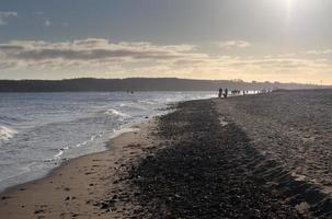 silhuetter av människor som pratar en promenad på en solig strand vid Östersjön i Tyskland. foto