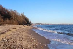 silhuetter av människor som pratar en promenad på en solig strand vid Östersjön i Tyskland. foto