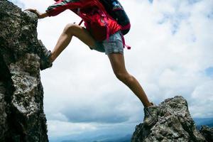 ung person vandring kvinna stående på toppen rock, ryggsäck kvinna tittar på vackra bergsdalen i solljus på sommaren, landskap med sport flicka, höga kullar, skog, himmel. resor och turism. foto