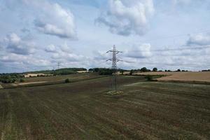 högspännings strömförsörjningsstolpar med kablar som går genom brittiska jordbruksmarker och landsbygd, hög vinkel från flygplan med drönarens kamera. foto