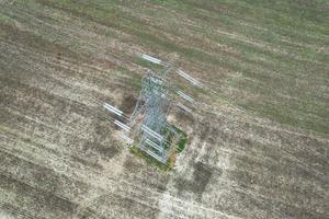 högspännings strömförsörjningsstolpar med kablar som går genom brittiska jordbruksmarker och landsbygd, hög vinkel från flygplan med drönarens kamera. foto