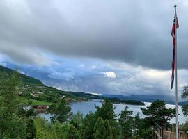 norge fjordar med små röda hus vid vattenbrynet och norsk flagga foto