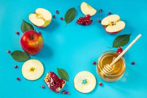 glad rosh hashanah. honung, äpplen och granatäpplen på blå bakgrund. rund ram för din text. judisk traditionell religiös högtid. foto