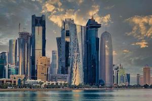 doha qatar skyline solnedgångsvy som visar finansdistriktet i västra viken med moderna skyskrapor, bilar, träd och moln på himlen. foto