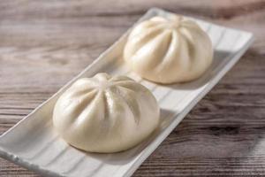 läcker baozi, kinesisk ångad köttbulle är redo att äta på serveringsfat och ångbåt, närbild, kopieringsutrymme produktdesignkoncept. foto