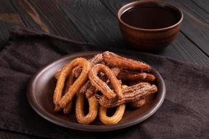 hemlagad churros med choklad på en mörk trä rustik bakgrund. foto