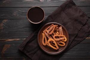 hemlagad churros med choklad på en mörk trä rustik bakgrund. foto