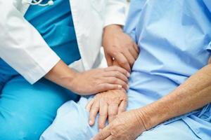 läkare som tar hand om, hjälper och uppmuntrar asiatisk äldre äldre kvinna patient på kliniken sjukhus. foto