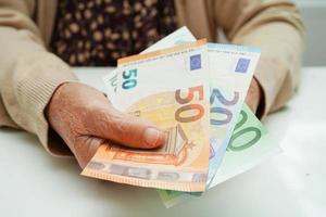 pensionerad äldre kvinna som håller eurosedlar pengar och oroa sig för månatliga utgifter och betalning av behandlingsavgift. foto