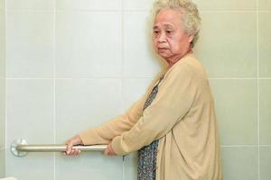 asiatisk äldre gammal kvinna patientanvändning toalettstödskena i badrummet, räckesäkerhetshandtag, säkerhet på vårdsjukhus. foto
