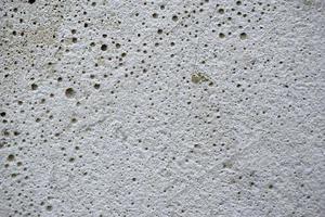 grå bakgrund av en betongvägg med hål och sprickor. vacker putsad vägg i huset. foto