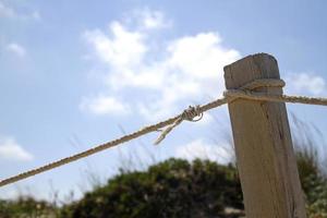 trästolpe med rep på stranden en solig dag foto