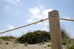 trästolpe med rep på stranden en solig dag foto