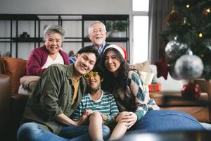 porträtt asiatisk familj nära julgran tillsammans hemma. familj, generation, jul och människor koncept foto