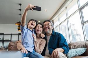 familj ler mot kameran. lycklig familj tar en selfie, ler mot en telefon hemma. foto