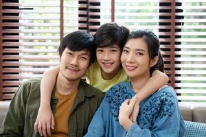 porträtt av glad asiatisk familj som spenderar tid tillsammans på soffan i vardagsrummet. familj och hem koncept. foto