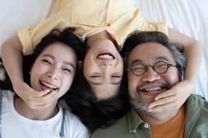 porträtt av glad asiatisk familj på sängen. familj och hem koncept. foto