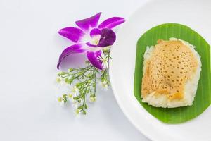 klibbigt ris med ångad vaniljsås på bananblad och fat med orkidéblomma, sött klibbigt ris, thailändsk söt dessert, original thaimat foto