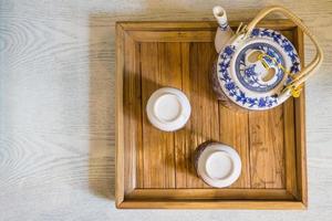 toppen av traditionell vit kopp te och tekanna i träbricka närbild på bordet foto