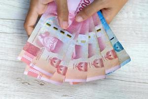 rupiah sedel i asiatisk kvinnas hand foto