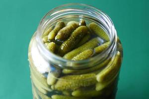 flaska inlagda gurkor, pickles på bordet foto