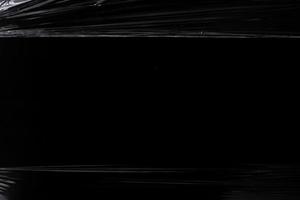 en svart transparent plaststruktur med hål för affisch och omslagskonst. realistisk plastfolie för överlagring, kopieringsutrymme och fotoeffekt. skrynklig plastyta på svart bakgrund foto