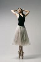 ballerina i bodysuit och vit kjol improviserar klassisk och modern koreografi i en fotostudio foto