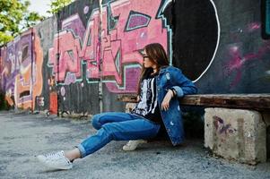 snygg casual hipster flicka i jeans slitage och glasögon mot stor graffiti vägg. foto