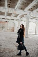 brunett snygg casual tjej i halsduk och handväska mot övergiven fabriksplats. foto