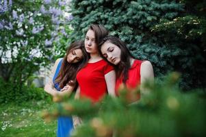 tre tonåringar flicka i blå och röda klänningar poserade utomhus. foto