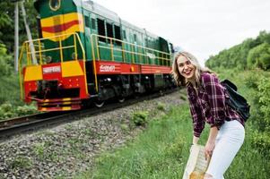 porträtt av en ung blondin i tartanskjorta bredvid tåget med en karta. foto